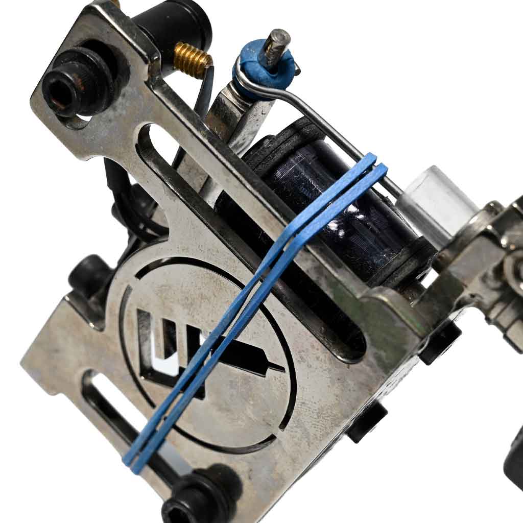 Close-up of a blue rubber band attached to a tattoo machine to reduce needle vibration.