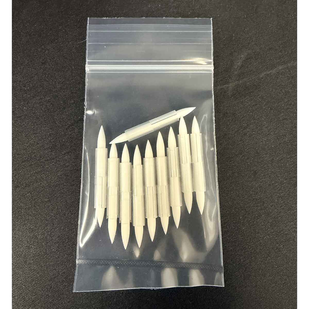 Set of tattoo needles in a clear plastic bag on a dark background